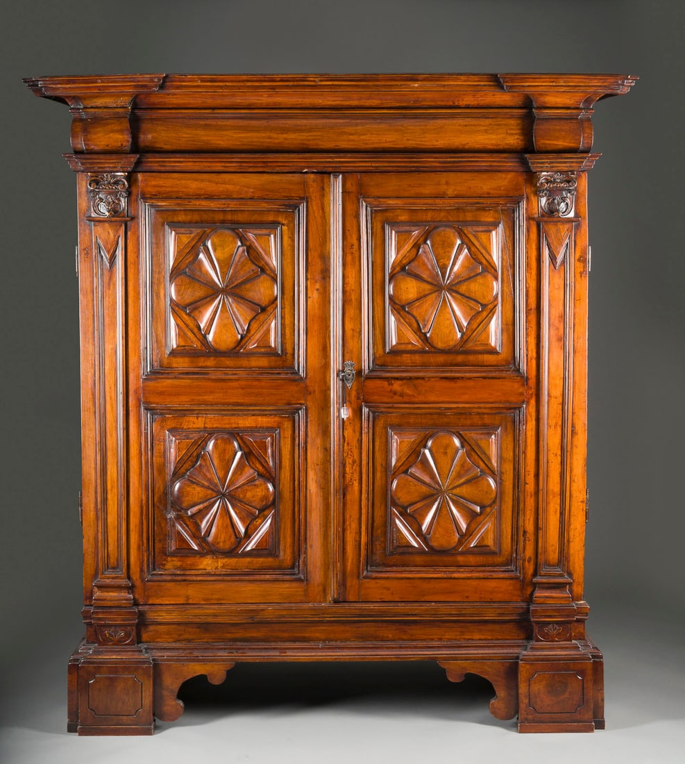 | LOUIS XIII SCHRANK: LOUIS XIII SCHRANK Wohl Frankreich, um 1700 Nussbaum, massiv gearbeitet, zweitürig, geschnitzte Kassetten mit Blütenform. H. 191,5, B 171,5, T. 86 cm. Hochrechteckiger, zweitüriger Korpus mit