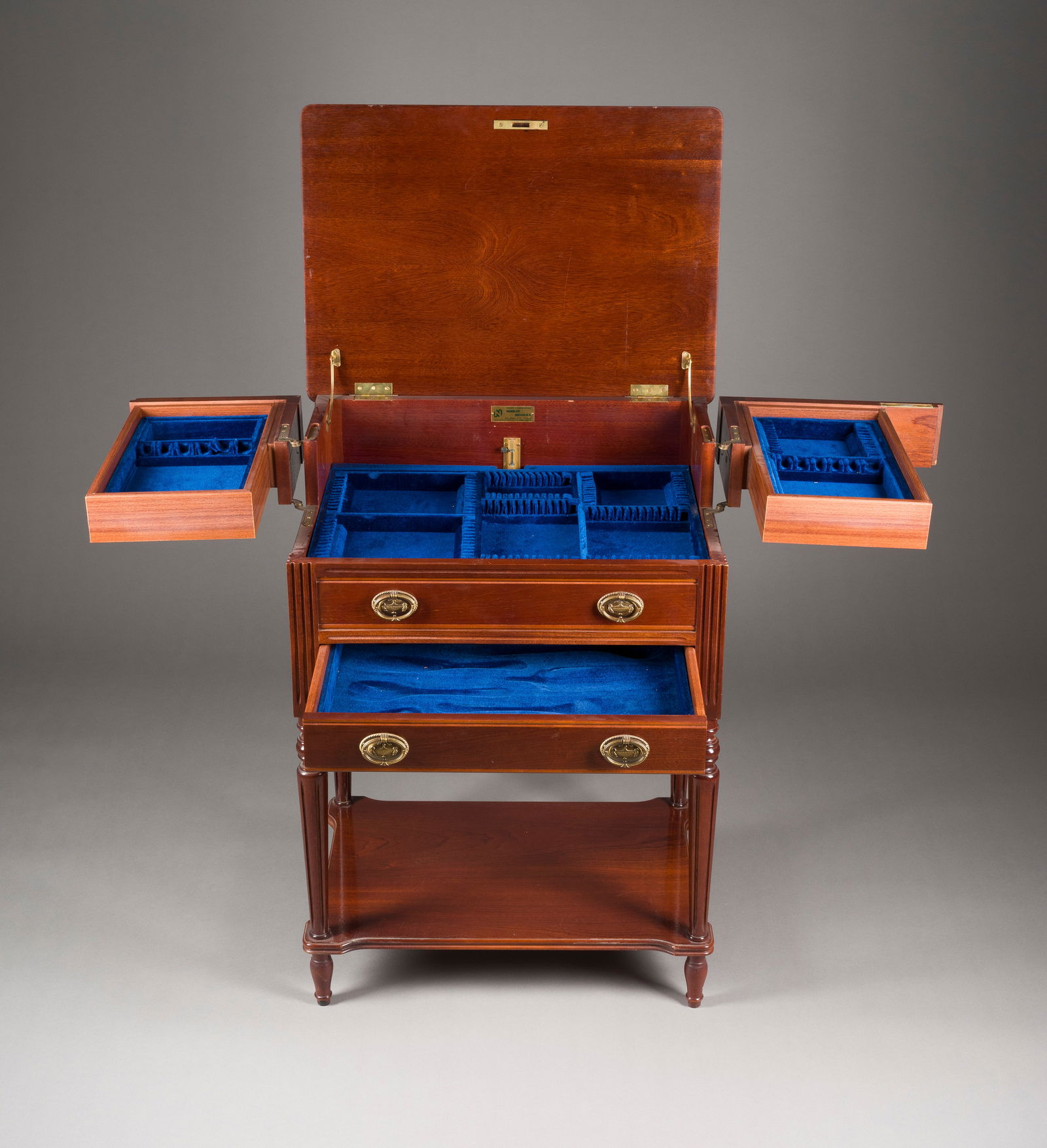 | SILBER BESTECKSCHRANK IM EMPIRE STIL: SILBER BESTECKSCHRANK IM EMPIRE STIL Barkaldo, Spanien, 20. Jh. Nussbaum, vergoldete Messingapplikationen, aufklappbar, mit Schlüssel. H. 86, B. 63, T. 45 cm. Innen bezeichnet 'Neguri S.A.. Part