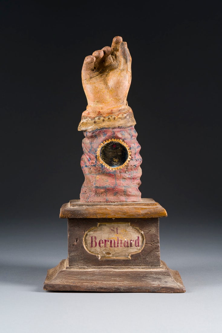| ARMRELIQUIAR DES HEILIGEN ABTES BERNHARD: ARMRELIQUIAR DES HEILIGEN ABTES BERNHARD Vermutlich Frankreich, 18. Jh. Holz, rundansichtig geschnitzt, vergoldet, polychrom gefasst, mittig eingelassenes Reliquienfenster mit Glasabdeckung, auf einem
