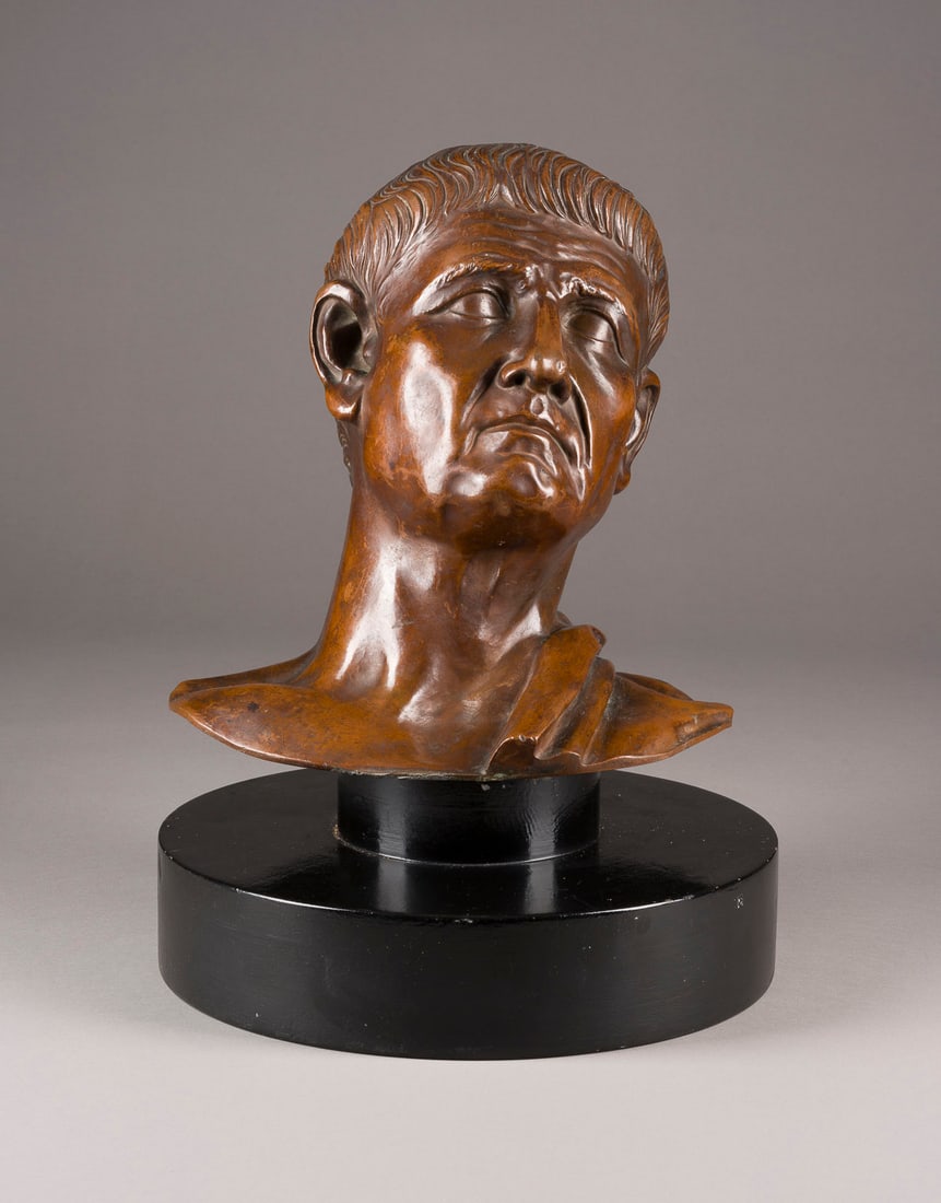 UNBEKANNTER BILDPLASTIKER | BÜSTE DES RÖMISCHEN KAISERS TIB: UNBEKANNTER BILDPLASTIKER Tätig um 1900 BÜSTE DES RÖMISCHEN KAISERS TIBERIUS Bronze, braun patiniert, auf rundem Sockel (H. 12, Dm. 32 cm). Figur H. 32, B. 28, T. 18 cm. Unsigniert. Part. Verlust d