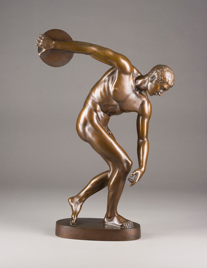RICHARD SCHEIBE | DISKOBOL DES MYRON (NACH ANTIKEM VORBILD): RICHARD SCHEIBE 1879 Chemnitz - 1964 Berlin DISKOBOL DES MYRON (NACH ANTIKEM VORBILD) Bronze, dunkel patiniert, auf ovaler Plinthe (H. 4 cm). Ges.-H. 58,5, B. 39, T. 15 cm, Gew. ca. 11,88kg. Auf der P