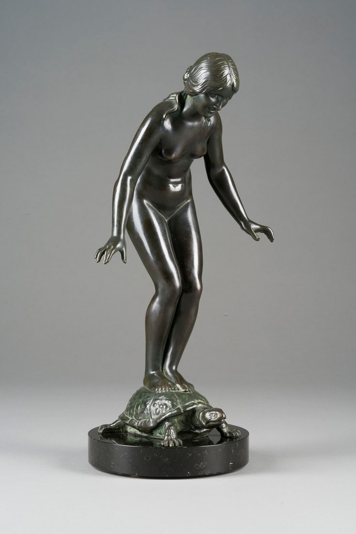 RICHARD FABRICIUS | FRAUENAKT AUF SCHILDKRÖTE STEHEND: RICHARD FABRICIUS 1863 Berlin - 1923 Dresden FRAUENAKT AUF SCHILDKRÖTE STEHEND Galvanoguss, dunkel patiniert, auf rundem Marmorsockel (H. 3 cm). Ges.-H. 37, B. 18,5, T. 15,5 cm. Auf der Schildkröte