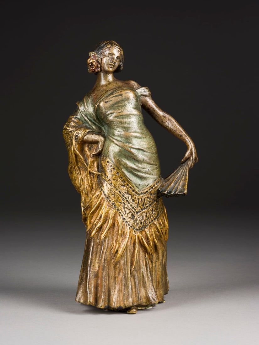 RAPHAËL NANNINI | SPANISCHE TÄNZERIN MIT FÄCHER: RAPHAËL NANNINI 1852 Florenz - 1925 Lastra a Signa SPANISCHE TÄNZERIN MIT FÄCHER Bronze, golden patiniert. H. 28,5, B. 14,5, T. 12 cm. Rückseitig am Kleid bezeichnet 'Nannini'. Verlust der Patina