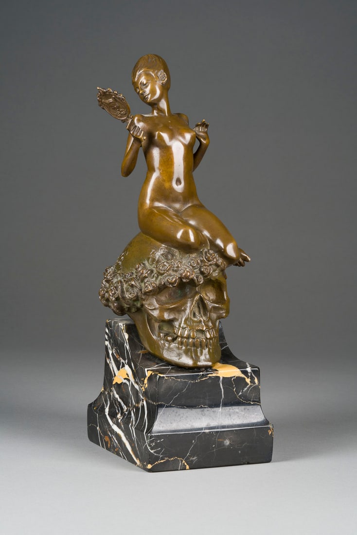 JOHAN WOLFGANG (JOHN W.) ELISCHER | FRAUENAKT MIT SPIEGEL A: JOHAN WOLFGANG (JOHN W.) ELISCHER 1891 Wien - 1966 Australien FRAUENAKT MIT SPIEGEL AUF EINEM TOTENKOPF SITZEND 1921 Bronze, braun patiniert, Marmorsockel (H. 8 cm. Ges.- H. 32, B. 10,5, T. 13 cm, Gew