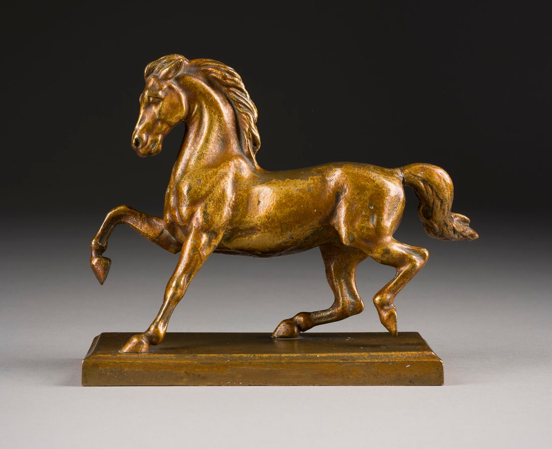 UNBEKANNTER BILDPLASTIKER | TRABENDES PFERD: UNBEKANNTER BILDPLASTIKER Tätig Anfang 20. Jh. TRABENDES PFERD Bronze, golden patiniert, auf rechteckiger Plinthe (H. 2 cm). Ges.-H. 15,5, B. 19, T. 8 cm, Gew. ca. 1,93kg. Part. Verlust der Patina,