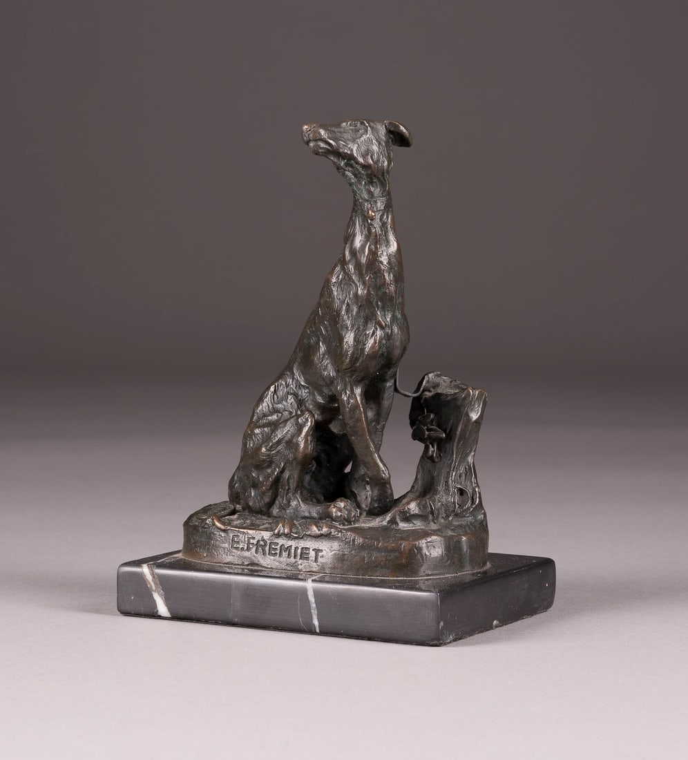 EMMANUEL FREMIET | SITZENDER WINDHUNDAM BAUMSTAMM: EMMANUEL FREMIET 1824 Paris - 1910 ebenda SITZENDER WINDHUNDAM BAUMSTAMM Bronze, dunkel patiniert, auf ovaler Plinthe und rechteckigem Marmorsockel (H. 2 cm). Ges.-H. 18, B. 12,5, T. 10 cm, Gew. ca.