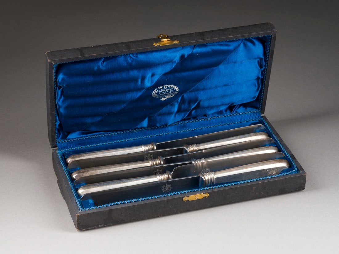 | SATZ VON SECHS SPEISEMESSERN MIT ORIGINALER KLINGE IM ORIGINALETUI: A SET OF SIX DINING KNIVES IN ORIGINAL CASE Russian, Riga, late 19th century The silver handle engraved with initials. Marked with city hallmark, 84 standard and master's mark 'EB'. The steel blade wi