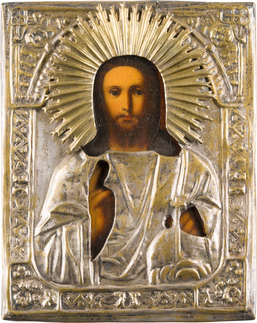 | KLEINE IKONE MIT CHRISTUS DEM WELTENHERRSCHER MIT OKLAD: A SMALL ICON SHOWING CHRIST THE SAVIOUR WITH OKLAD Russian, 19th century Oil on wood panel with cloth covering. The brass oklad chased and repousse. 22 x 17.7 cm.KLEINE IKONE MIT CHRISTUS DEM WELTENHE