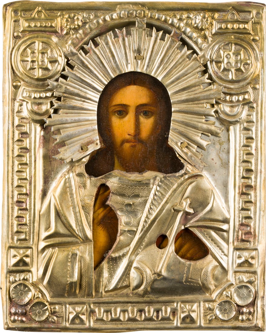 | KLEINE IKONE MIT CHRISTUS DEM WELTENHERRSCHER MIT OKLAD: A SMALL ICON SHOWING CHRIST THE SAVIOUR WITH OKLAD Russian, 19th century Oil on wood panel with cloth backing. The brass oklad chased and repousse. 22 x 17.8 cm.KLEINE IKONE MIT CHRISTUS DEM WELTENHER