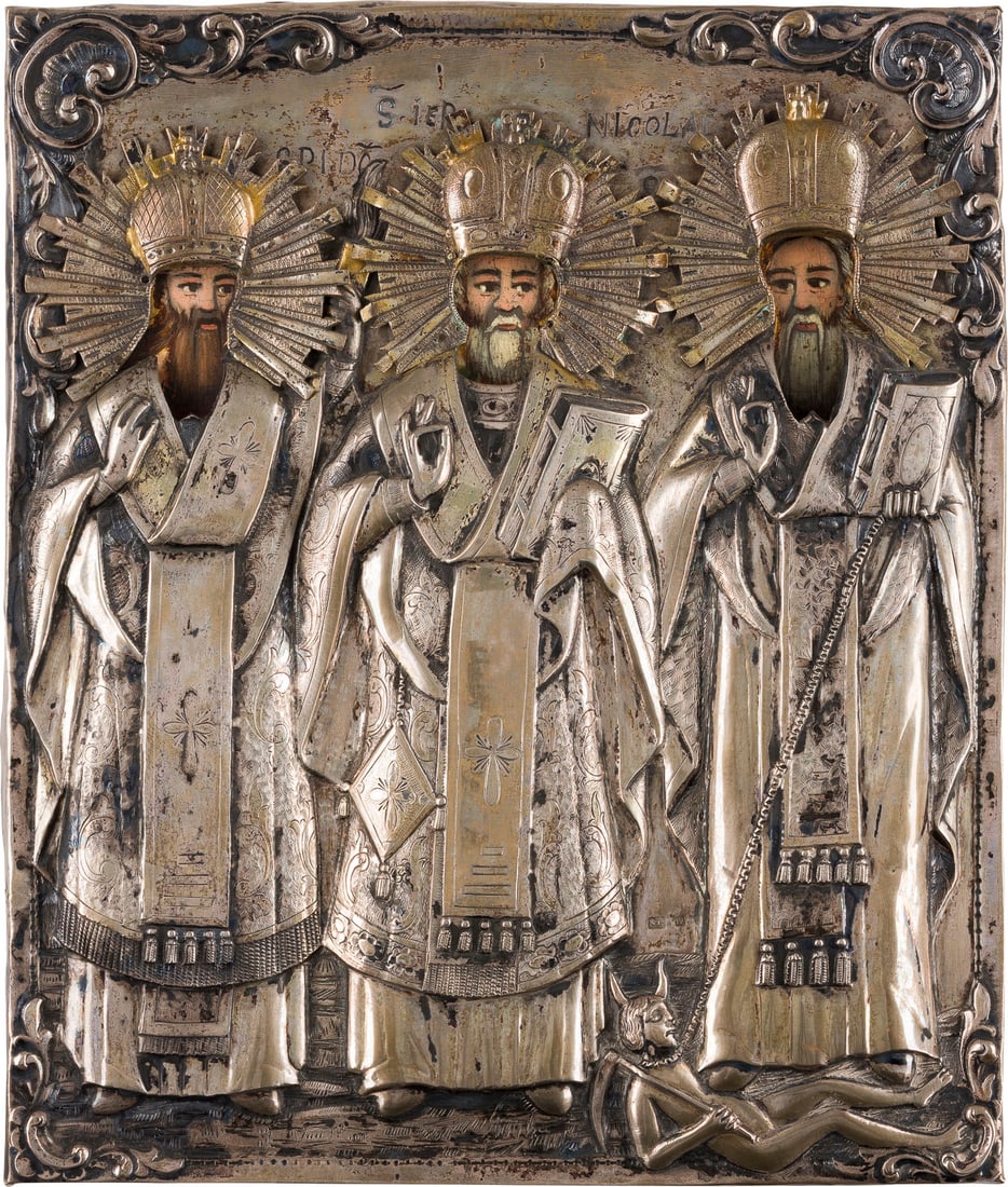 | DATIERTE IKONE MIT DEN HEILIGEN SPIRIDON, NIKOLAUS VON MYRA UND CHARALAMPOS MIT MASSIVEM: A DATED ICON WITH SAINTS SPYRIDON, NICHOLAS OF MYRA AND CHARALAMBOS WITH A MASSIVE SILVER OKLAD Romanian, dated 1859 Oil on wood panel. The border and haloes made of gold. The silver oklad chased and