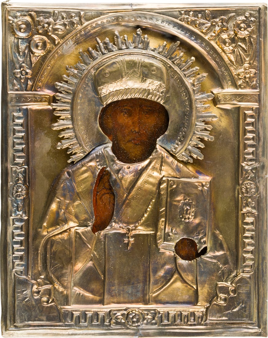 | KLEINE IKONE MIT DEM HEILIGEN NIKOLAUS VON MYRA MIT OKLAD: A SMALL ICON SHOWING ST. NICHOLAS OF MYRA WITH OKLAD Russian, 19th century Oil on wood panel. The brass oklad chased and repousse. Restored. 22 x 17.7 cm.KLEINE IKONE MIT DEM HEILIGEN NIKOLAUS VON MYR