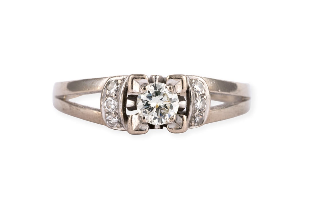 BRILLANT RING: BRILLANT RING WG 750. Ringmass: ca. 57. Ringbreite: ca. 6,0 mm. Ges.-Gew.: ca. 3,9 g. Ring, besetzt mit einem zentralen Brillanten von ca. 0.25 ct. G/VVS, flankiert von Diamanten im 8/8-Schliff zus.
