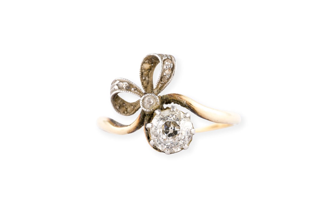 ROMANTISCHER BELLE EPOQUE RING: ROMANTISCHER BELLE EPOQUE RING PT/GG 585. Ringmass: ca. 50,5. Ges.-Gew.: ca. 2,2 g. Ring mit Schleifen-Motiv, besetzt mit einem Zentralen Diamanten im Altschliff von ca. 0.60 ct. I/P. Die restlichen