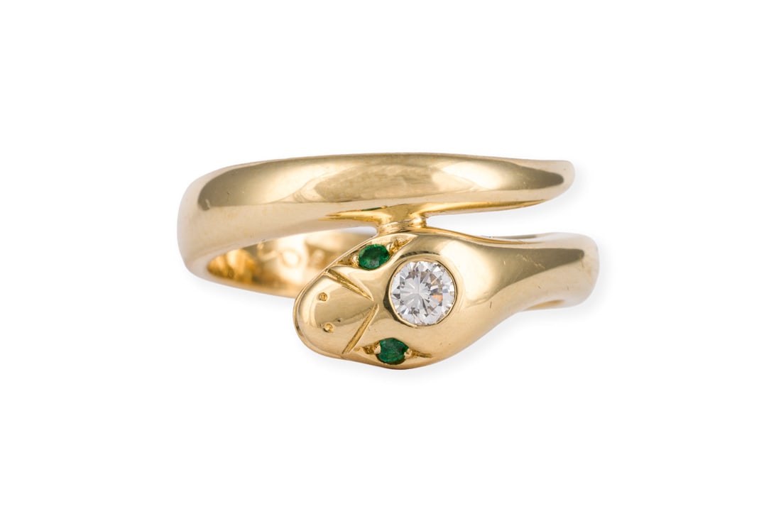 SCHLANGEN BRILLANT RING: SCHLANGEN BRILLANT RING GG 750. Ringmass: ca. 53. Ges.-Gew.: ca. 7,1 g. Schlangenring, besetzt mit einem Brillanten von ca. 0.15 ct. I/VVS, sowie wohl zwei Smaragde als Augen.