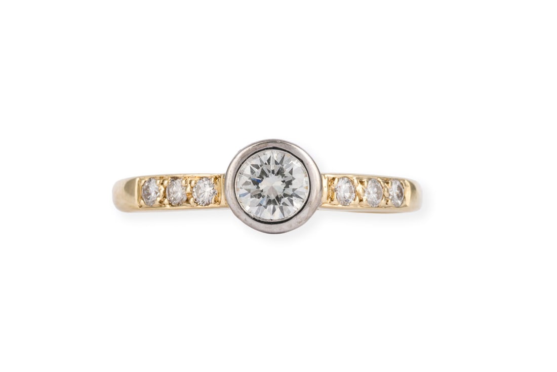 SOLITAER BRILLANT RING: SOLITAER BRILLANT RING WG/GG 585. Ringmass: ca. 49,5. Ges.-Gew.: ca. 2,0 g. Ring, besetzt mit einem zentralen Brillanten von ca. 0.30 ct. H/VS, sowie weitere Brillanten auf der Ringschiene zus. ca. 0.