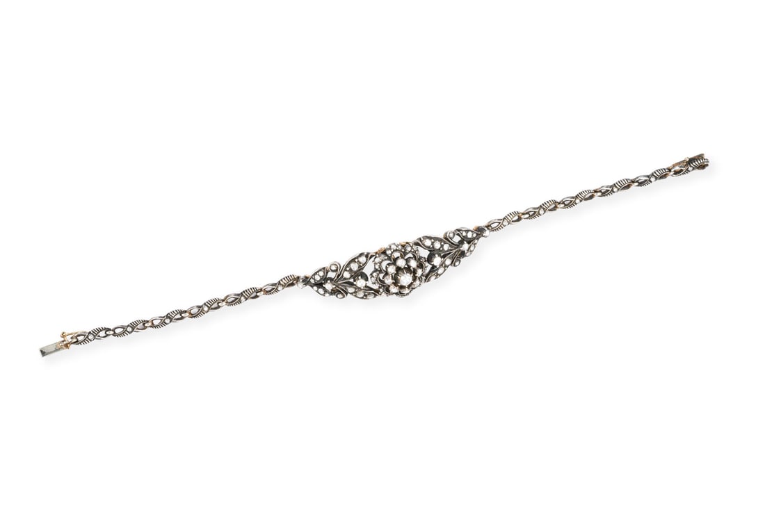 FLORALES ARMBAND 19. JH.: FLORALES ARMBAND 19. JH. AG/GG 585. L.: ca. 18,5 cm. B.: ca. 16,5 mm. Ges.-Gew.: ca. 18,2 g. Armband im floralen Design, besetzt mit Rosendiamanten zus. ca. 1.00 ct. Kastenschloss mit Sicherheitsacht.