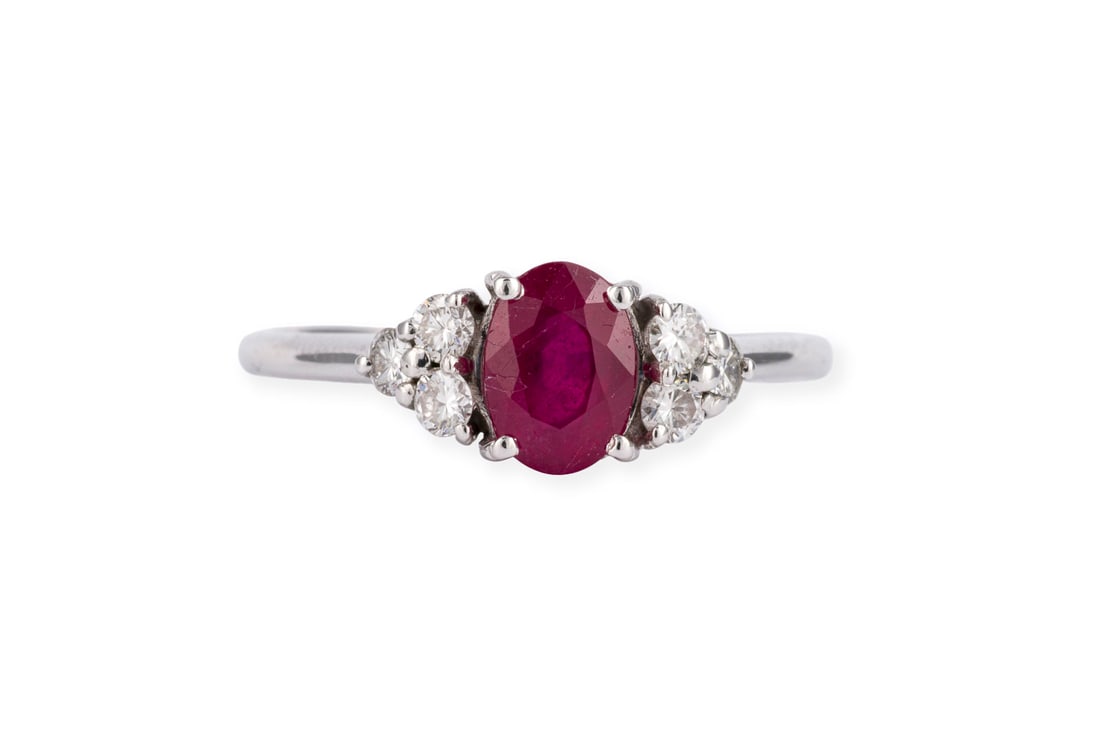 RUBIN BRILLANT RING: RUBIN BRILLANT RING WG 750. Ringmass: ca. 56. Ringkopfmasse: ca. 13,0 x 7,0 mm. Ges.-Gew.: ca. 2,8 g. Ring, besetzt mit einem zentralen Rubin von ca. 1.04 ct., flankiert von 6 Brillanten zus. ca.