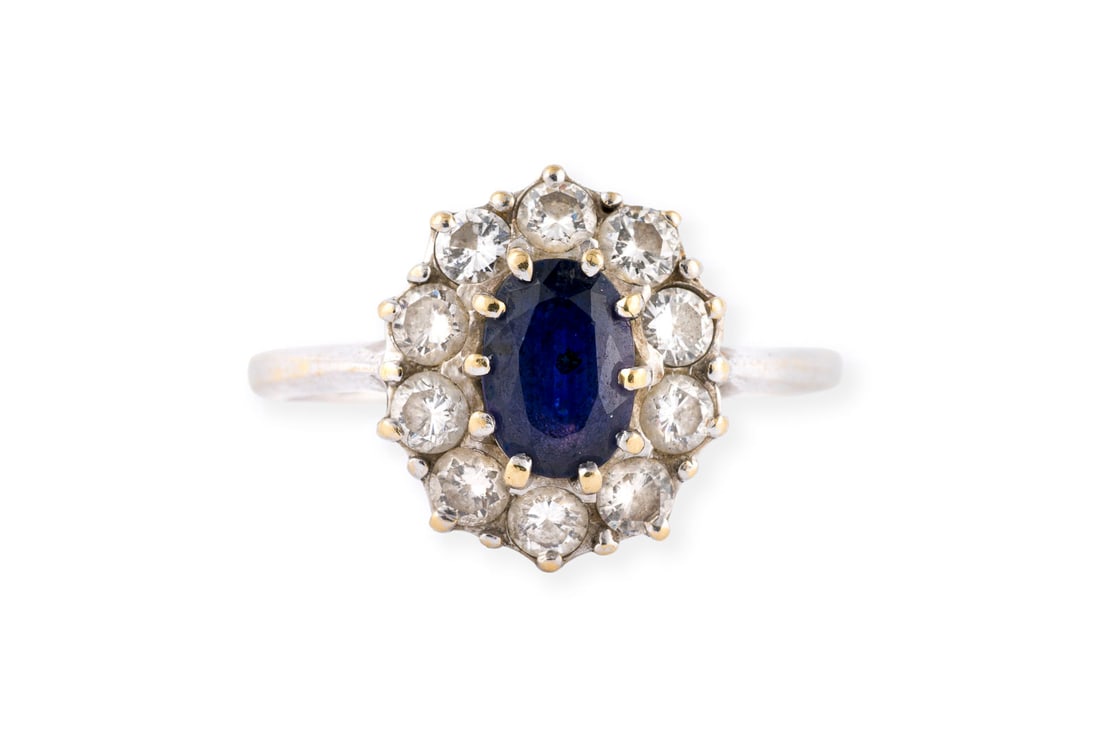SAPHIR ENTOURAGE RING: SAPHIR ENTOURAGE RING WG 750. Ringmass: ca. 54. Ringkopfmasse: ca. 13,2 x 11,5 mm. Ges.-Gew.: ca. 4,1 g. Ring, besetzt mit einem zentralen Saphir von ca. 0.80 ct. und einem Kranz aus Brillanten zus.