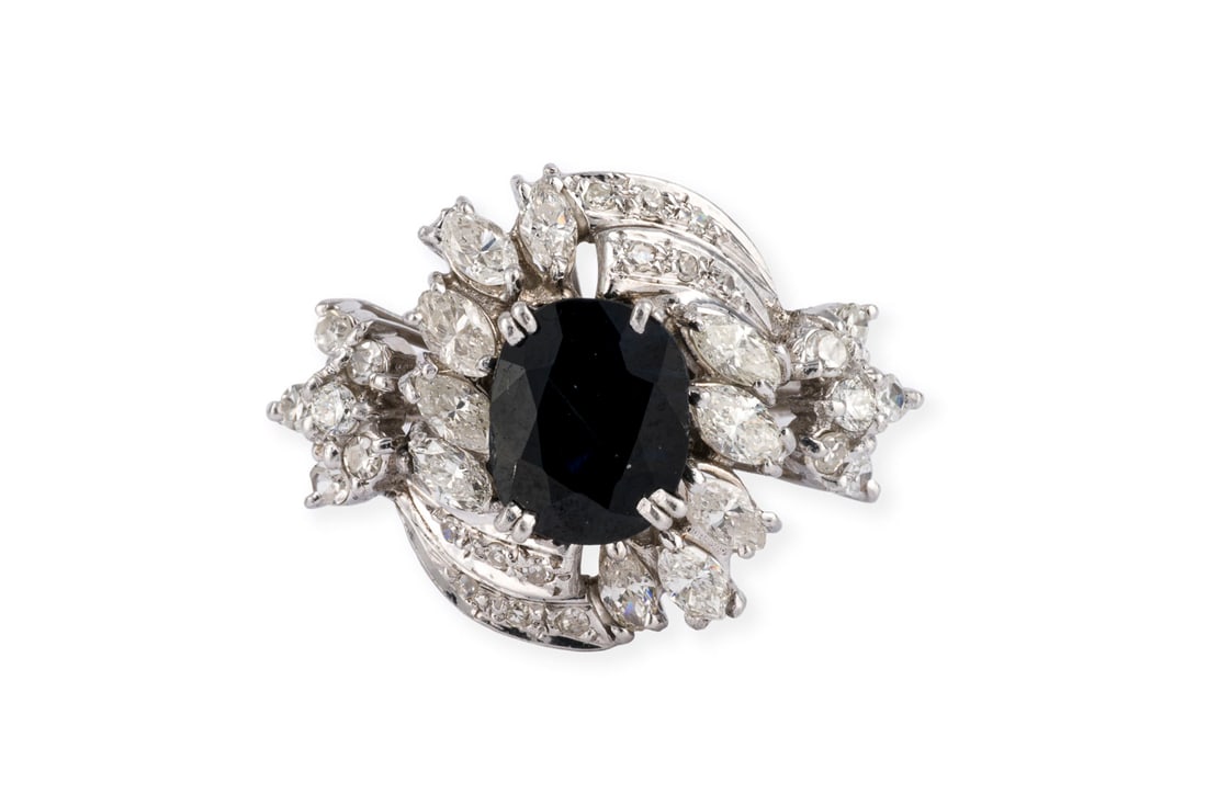 SAPHIR COCKTAIL RING: SAPHIR COCKTAIL RING 750 WG. Ringmass: ca. 54. Ringkopfmasse: ca. 21,4 x 15,6 mm. Ges.-Gew.: ca. 5,2 g. Ring, besetzt einem zentralen Saphir von ca. 1.50 ct., sowie Diamanten im Marquise- und