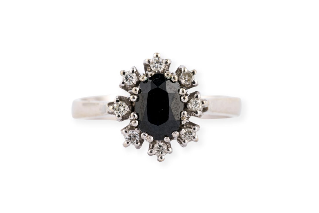 SAPHIR ENTOURAGE RING: SAPHIR ENTOURAGE RING WG 585 (getestet). Ringmass: ca. 50. Ringkopfmasse: ca. 11,4 x 10,4 mm. Ges.-Gew.: ca. 3,5 g. Ring, besetzt mit einem zentralen Saphir von ca. 0.80 ct. und einem Kranz aus