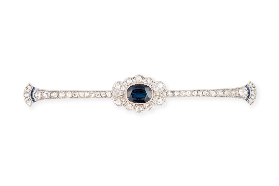 SAPHIR ART DECO BROSCHE: SAPHIR ART DECO BROSCHE PT/GG 750 (getestet). Masse: ca. 79,5 x 13,2 mm. Ges.-Gew.: ca. 6,2 g. Art DEco Brosche, besetzt mit einem zentralen Saphir von ca. 1.50 ct. und Rosendiamanten zus. ca. 0.50