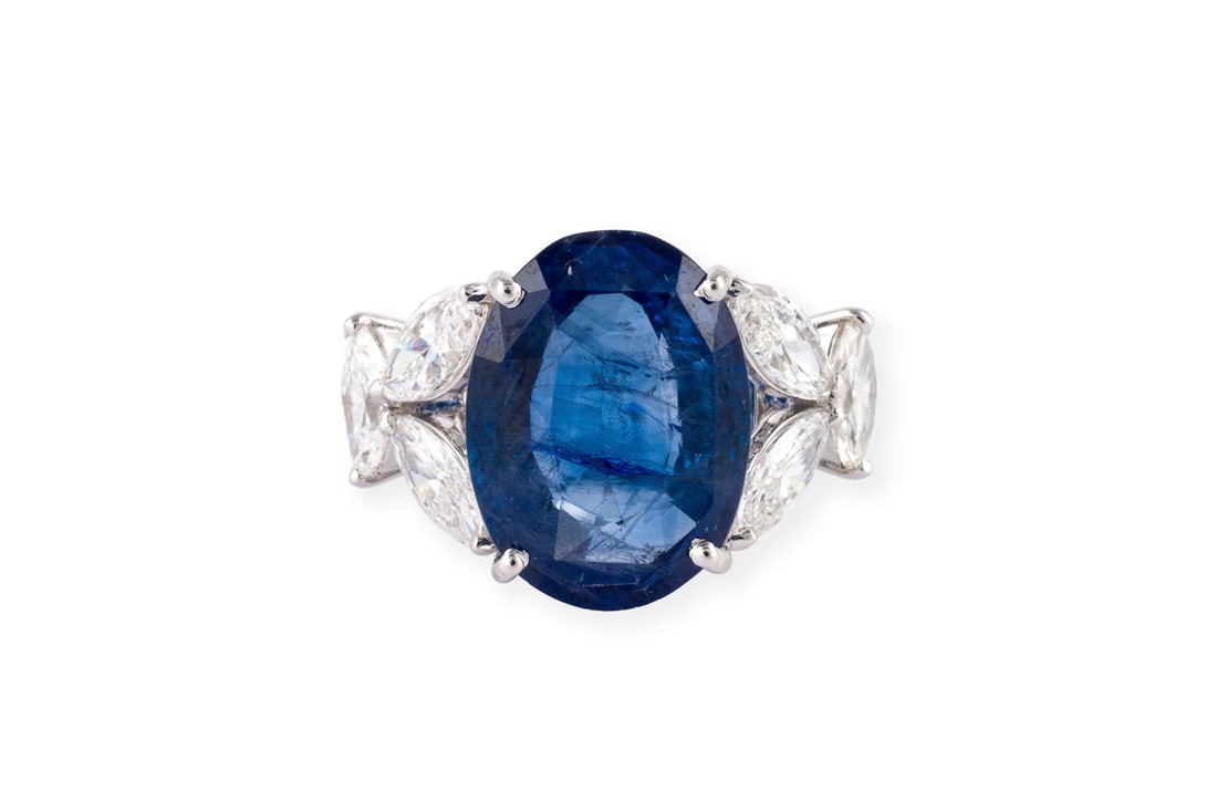 SAPHIR RING 8.00 CT.: SAPHIR RING 8.00 CT. WG 585. Ringmass: ca. 54. Ges.-Gew.: ca. 5,3 g. Ring, besetzt mit einem zentralen, ovalen Saphir von ca. 8.00 ct., umgeben von Diamanten im Marquiseschliff zus. ca. 1.73 ct.
