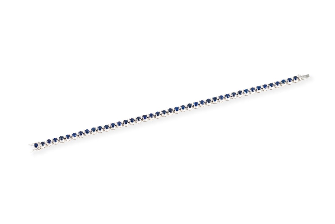 SAPHIR TENNIS ARMBAND: SAPHIR TENNIS ARMBAND WG 750. L.: ca. 18,0 cm. B.: ca. 4,1 mm. Ges.-Gew.: ca. 13,8 g. Tennisarmband, besetzt mit Saphiren zus. ca. 5.70 ct. Kastenschloss mit doppelter Sicherheitsacht.