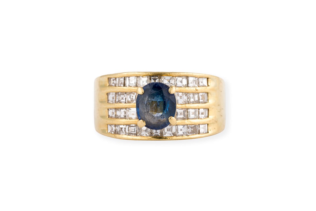 SAPHIR BANDRING: SAPHIR BANDRING GG 585 (getestet). Ringmass: ca. 58. Ringbreite: ca. 10,7 mm. Ges.-Gew.: ca. 7,8 g. Bandring, besetzt mit einem zentralen Saphir wohl synthetisch von ca. 1.15 ct. und mehrreihige