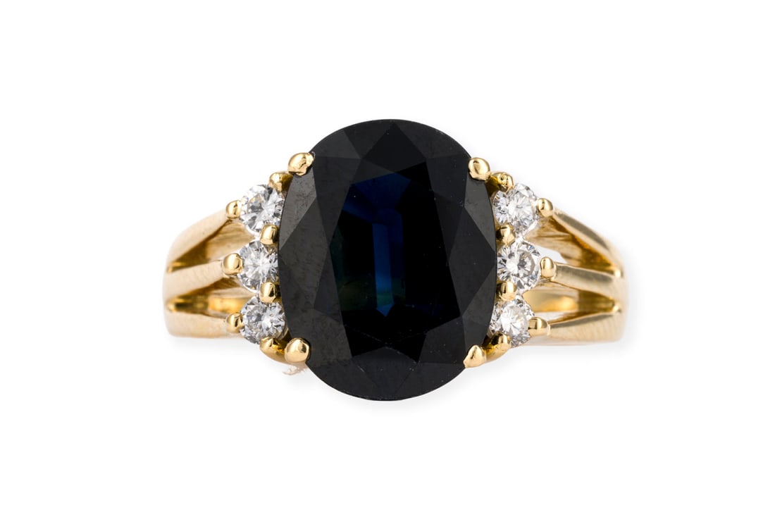 SAPHIR RING: SAPHIR RING GG 750. Ringmass: ca. 54. Ringkopfmasse: ca. 12,3 x 14,5 mm. Ges.-Gew.: ca. 7,9 g. Ring, besetzt mit einem zentralen Saphir von ca. 4.08 ct., flankiert von 6 Brillanten zus. ca. 0.24 ct.