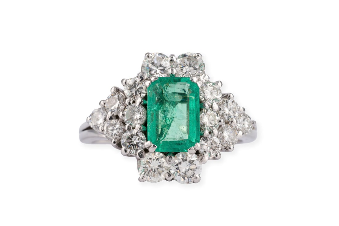 SMARAGD BRILLANT RING: SMARAGD BRILLANT RING WG 585. Ringmass: ca. 56,5. Ringkopfmasse: ca. 15,6 x 20,1 m. Ges.-Gew.: ca. 7,1 g. Ring, besetzt mit einem zentralen Smaragd im Smaragdschliff von ca. 1.32 ct. und reichlich Bri