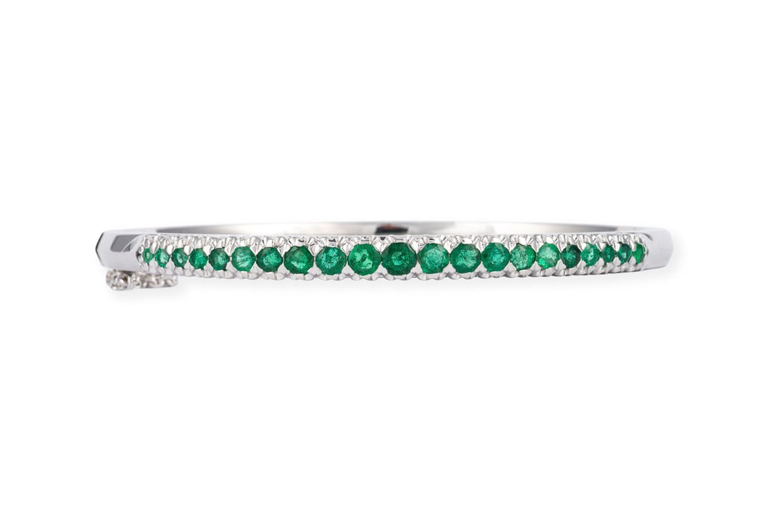 SMARAGD ARMREIF: SMARAGD ARMREIF WG 750. D.(innen): ca. 59,0 mm. B.: ca. 4,8 mm. Ges.-Gew.: ca. 21,4 g. Armreif, besetzt mit Smaragden zus. ca. 1.30 ct. Kastenschloss mit Sicherheitskette.