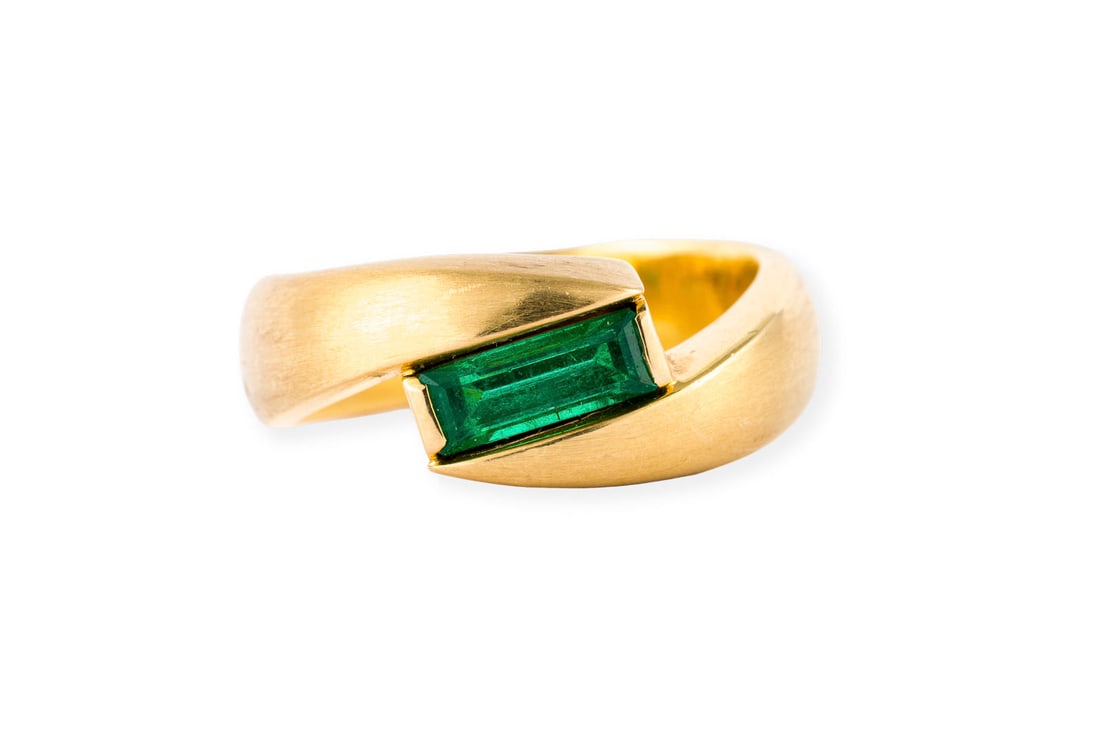SMARAGD DESIGN RING: SMARAGD DESIGN RING GG 750. Ringmass: ca. 57. Ringbreite: ca. 8,6 mm. Ges.-Gew.: ca. 12,7 g. Mattierter Ring, besetzt mit einem Smaragd von ca. 0.75 ct.
