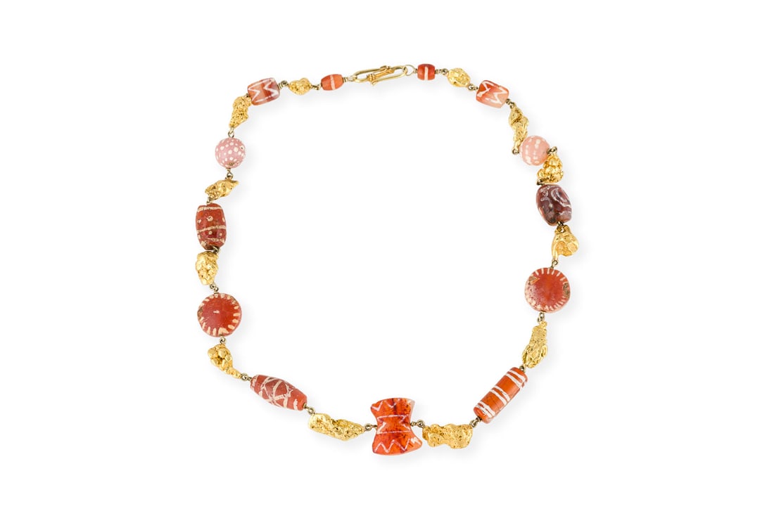 AUSSERGEWOHNLICHES KARNEOL GOLDNUGGET COLLIER: AUSSERGEWOHNLICHES KARNEOL GOLDNUGGET COLLIER GG 900-999 (getestet). L.: ca. 41,0 cm. Ges.-Gew.: ca. 55,5 g. Collier, besetzt mit gemischten geaetzten Karneolperlen und Zwischenelementen aus Gold-Nugg
