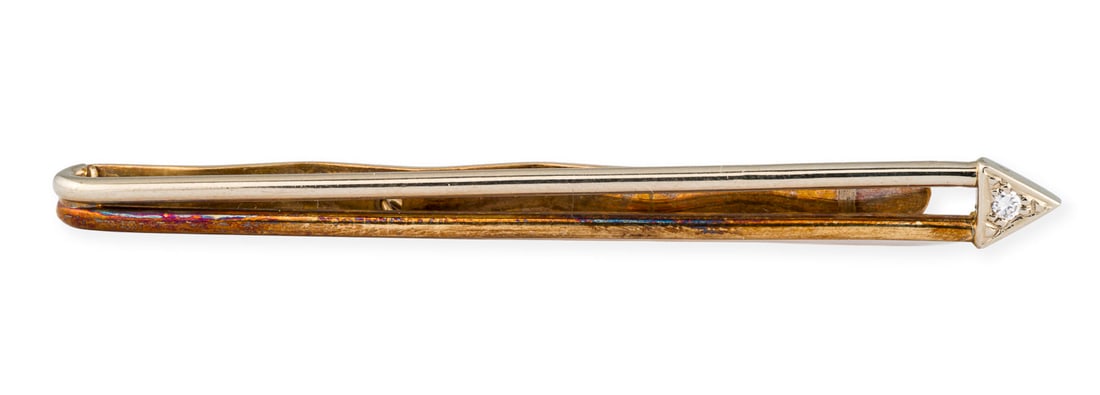 KRAVATTEN KLAMMER: KRAVATTEN KLAMMER WG/GG 585. Masse: ca. 61,0 x 5,5 mm. Ges.-Gew.: ca. 7,1 g. Bicolor-Kravattenklammer mit Pfeilspitze, besetzt mit einem Brillanten von ca. 0.02 ct.