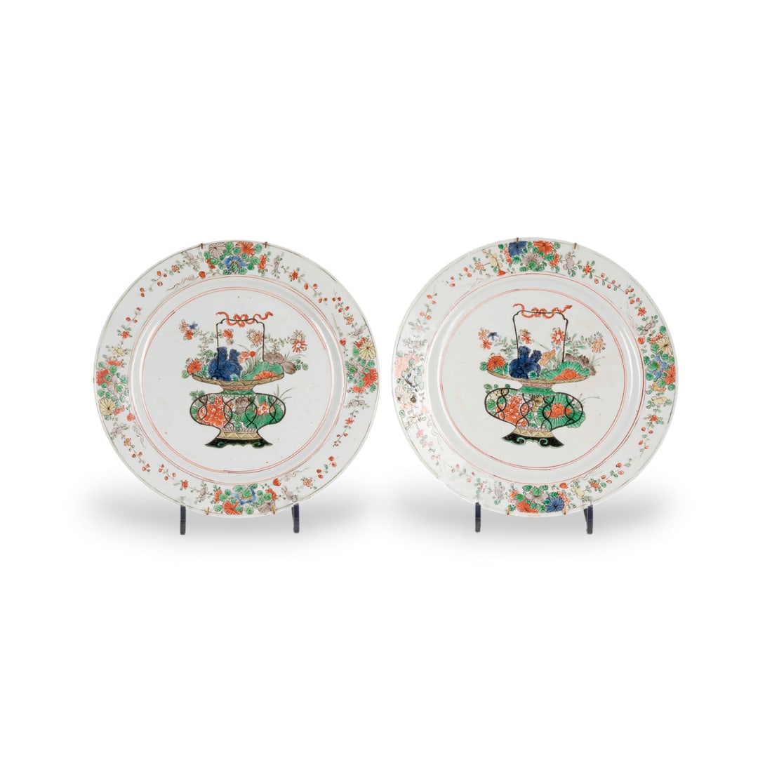 PAAR FAMILLE-VERTE-TELLER MIT BLUMENKORBDARSTELLUNG: A PAIR OF FAMILLE-VERTE 'FLOWER BASKET' DISHES China, Qing dynasty Porcelain. D. 26.5 cm. Both with a mark to the base. With traces of age and use, rim chips and abrasion; one damaged and restored, wi