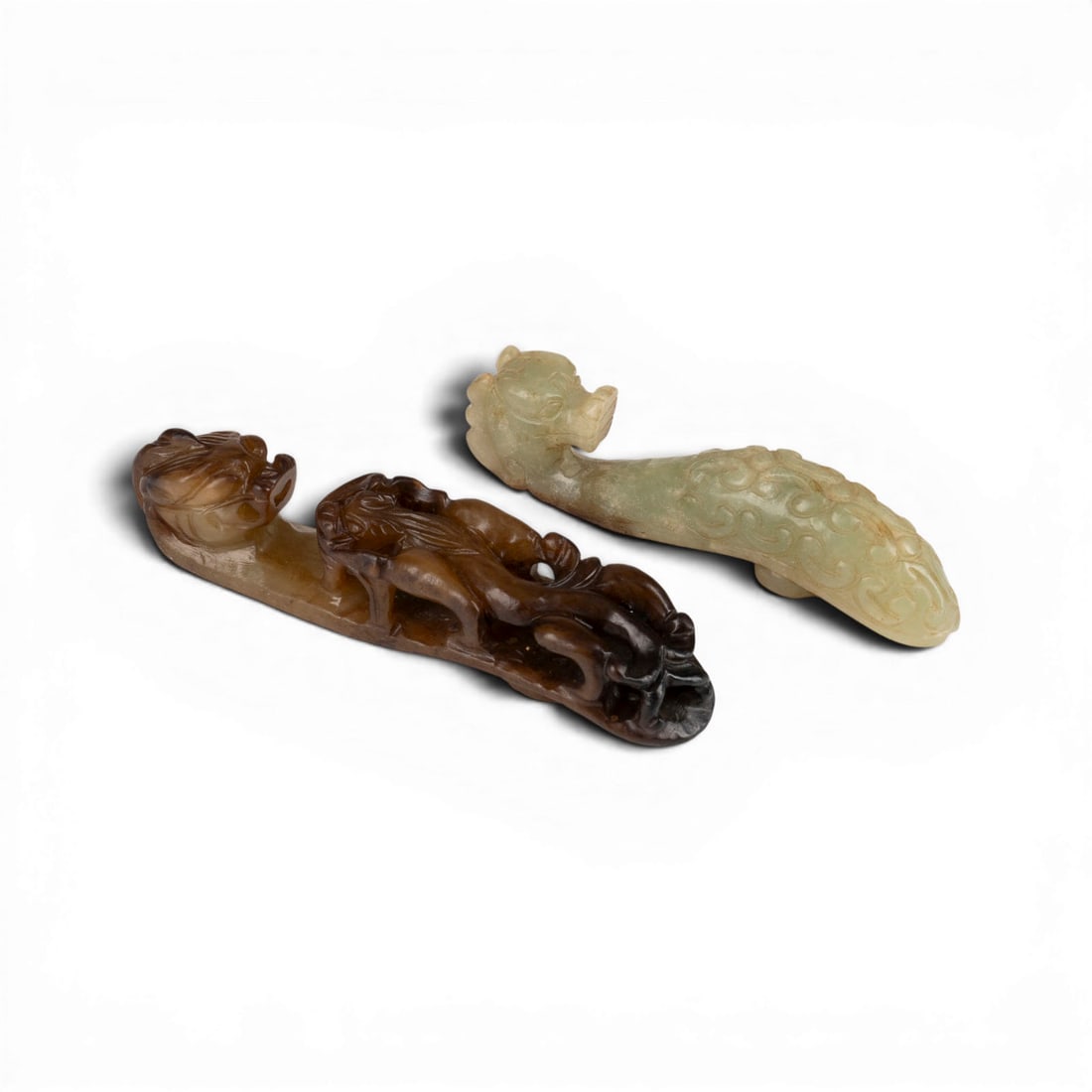 ZWEI GUERTELHAKEN AUS JADE: TWO JADE BELT HOOKS China Jade. L. 10-12 cm. With traces of age and use, one belt hook with a small chip.ZWEI GUERTELHAKEN AUS JADE China Jade. L. 10-12 cm. Mit Alters- und Gebrauchsspuren, ein Guerte
