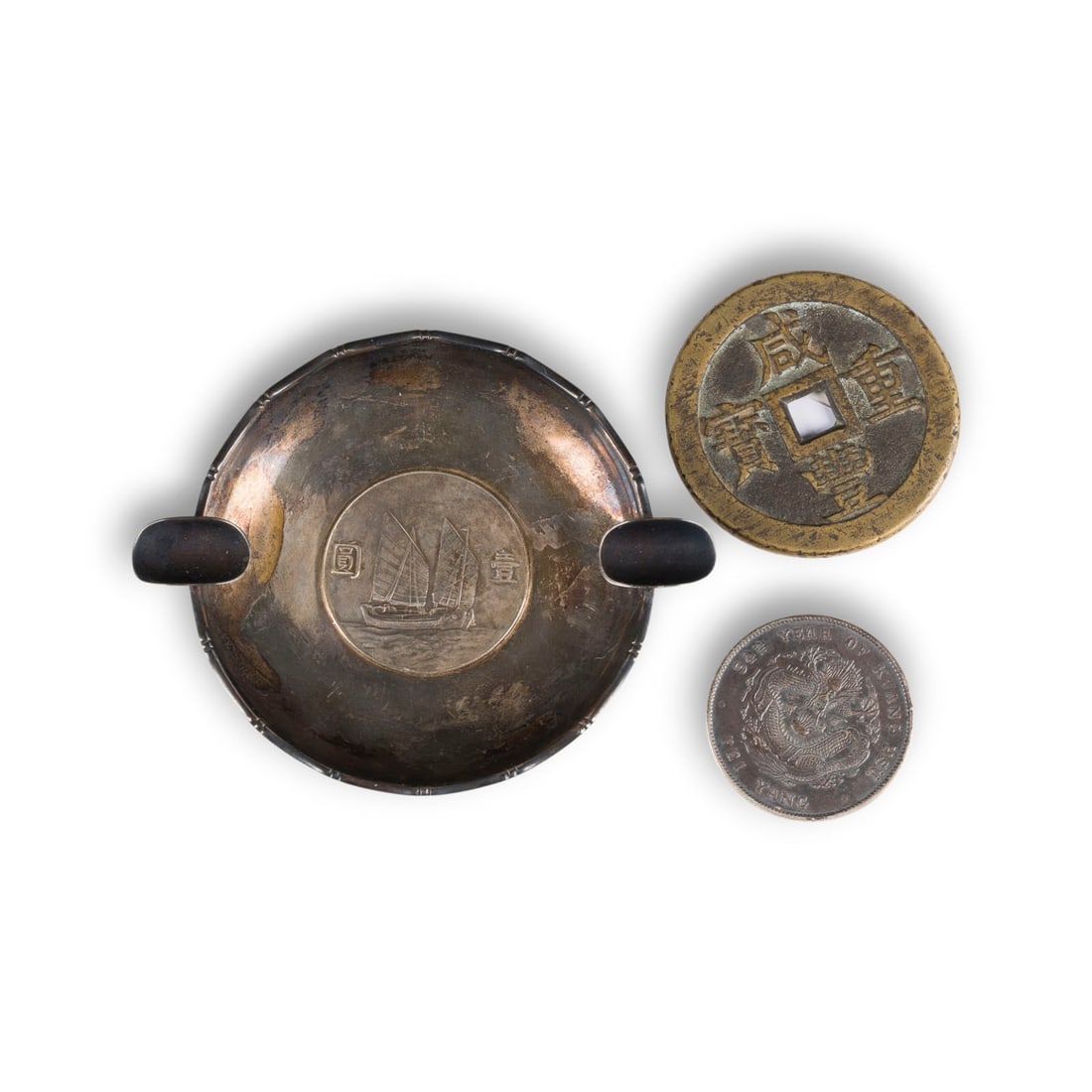 EIN KONVOLUT VON DREI CHINESISCHEN MUENZEN: A GROUP OF THREE CHINESE COINS China, 19th/20th century Silver/bronze. L. 3.8-10.8 cm. Including a 'Beiyang zao' Guangxu coin, a 'Xianfeng zhongbao' coin, and a 'Wai Kee' silver coin dish. With traces