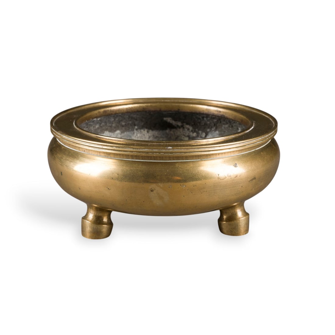 EIN POLIERTES DREIFUESSIGES RAEUCHERGEFAESS AUS BRONZE: A POLISHED BRONZE TRIPOD INCENSE BURNER China Bronze. H. 6.4 cm. With a 'Xuande' mark on the base. With traces of use, partially abraded and slightly chipped.EIN POLIERTES DREIFUESSIGES RAEUCHERGEFAES