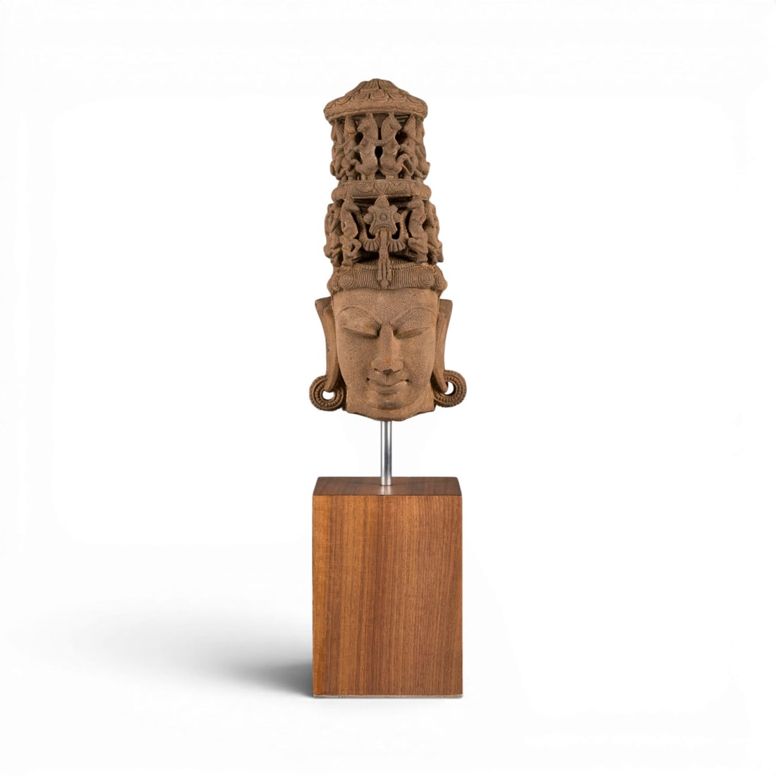 EIN SANDSTEINKOPF DES VISHNU: A SANDSTONE HEAD OF VISHNU North India, 11th/12th century Sandstone. H. 34 cm (63 cm with base). The head of Vishnu is exquisitely worked and displays a serene expression, characterised by almond-shap