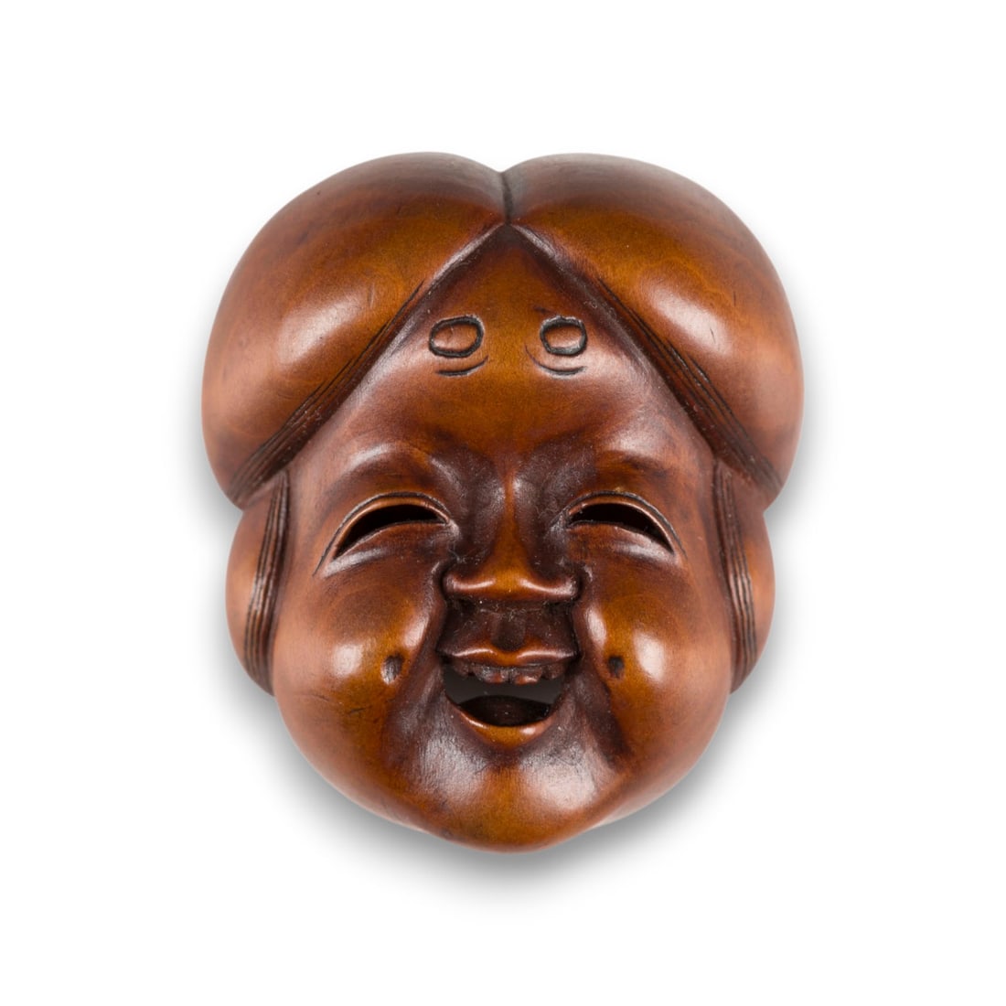 EIN NETSUKE IN FORM EINER OKAME AUS HOLZ: A WOOD MASK NETSUKE OF OKAME Japan, 19th century Wood. H. 4.7 cm. The chubby face shown typically smiling, her hair parted in the centre and with tenjo eyebrows on her forehead, signed Shuzan. With