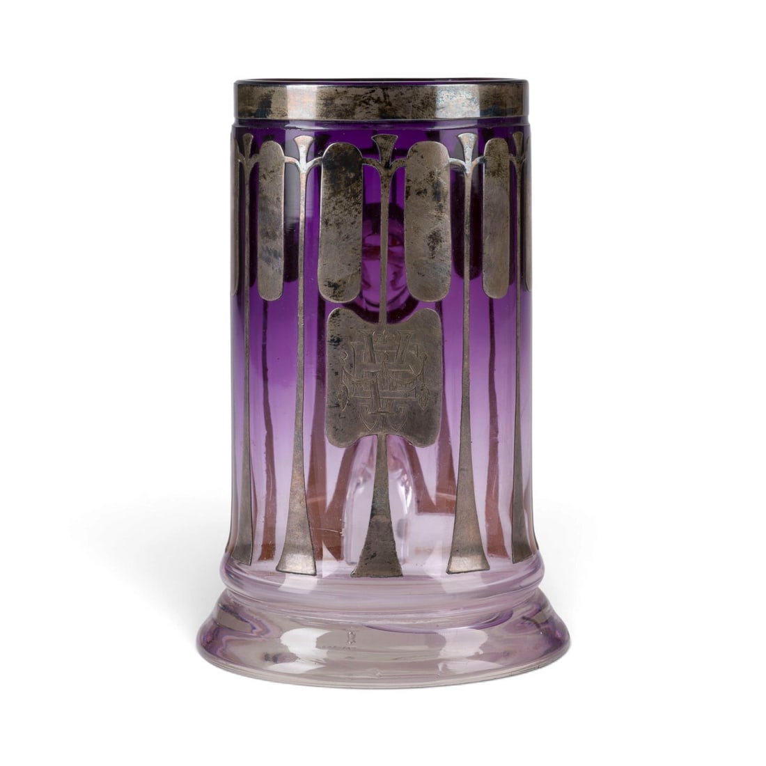 | BIERKRUG IM STIL VON JOSEF HOFFMANN: BIERKRUG IM STIL VON JOSEF HOFFMANN Wohl Boehmen, um 1900 Farbloses Glas, amethystfarbener Unterfang, Silberauflage. H. 15,2 cm. Mit Monogramm 'VE'. Haarriss.BIERKRUG IM STIL VON JOSEF HOFFMANN Wohl