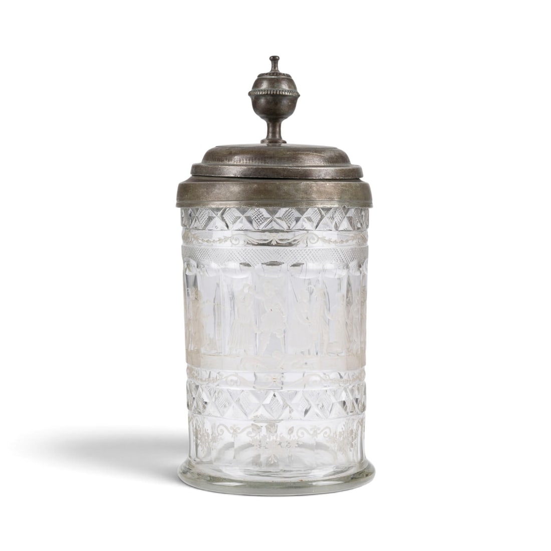 | WALZENKRUG MIT GESELLSCHAFTSSZENE: WALZENKRUG MIT GESELLSCHAFTSSZENE Deutsch, 19. Jh. Farbloses Glas, geschliffen, geschnitten, Zinnmontierung. H. 25 cm (mit Daumenrast).WALZENKRUG MIT GESELLSCHAFTSSZENE Deutsch, 19. Jh. Farbloses