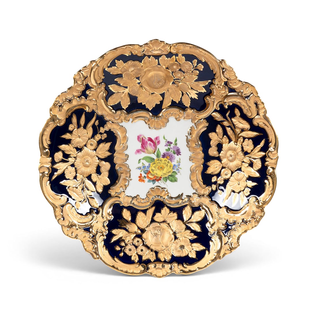 | KOBALTBLAUE PRUNKSCHALE MIT BLUMENMALEREI: KOBALTBLAUE PRUNKSCHALE MIT BLUMENMALEREI Deutsch, Meissen, 1977 Porzellan, kobaltblauer Fond, polychrome Malerei, glaenzende und matte Goldstaffage. D. 30,5 cm. Unterglasurblaue Schwertermarke, Press