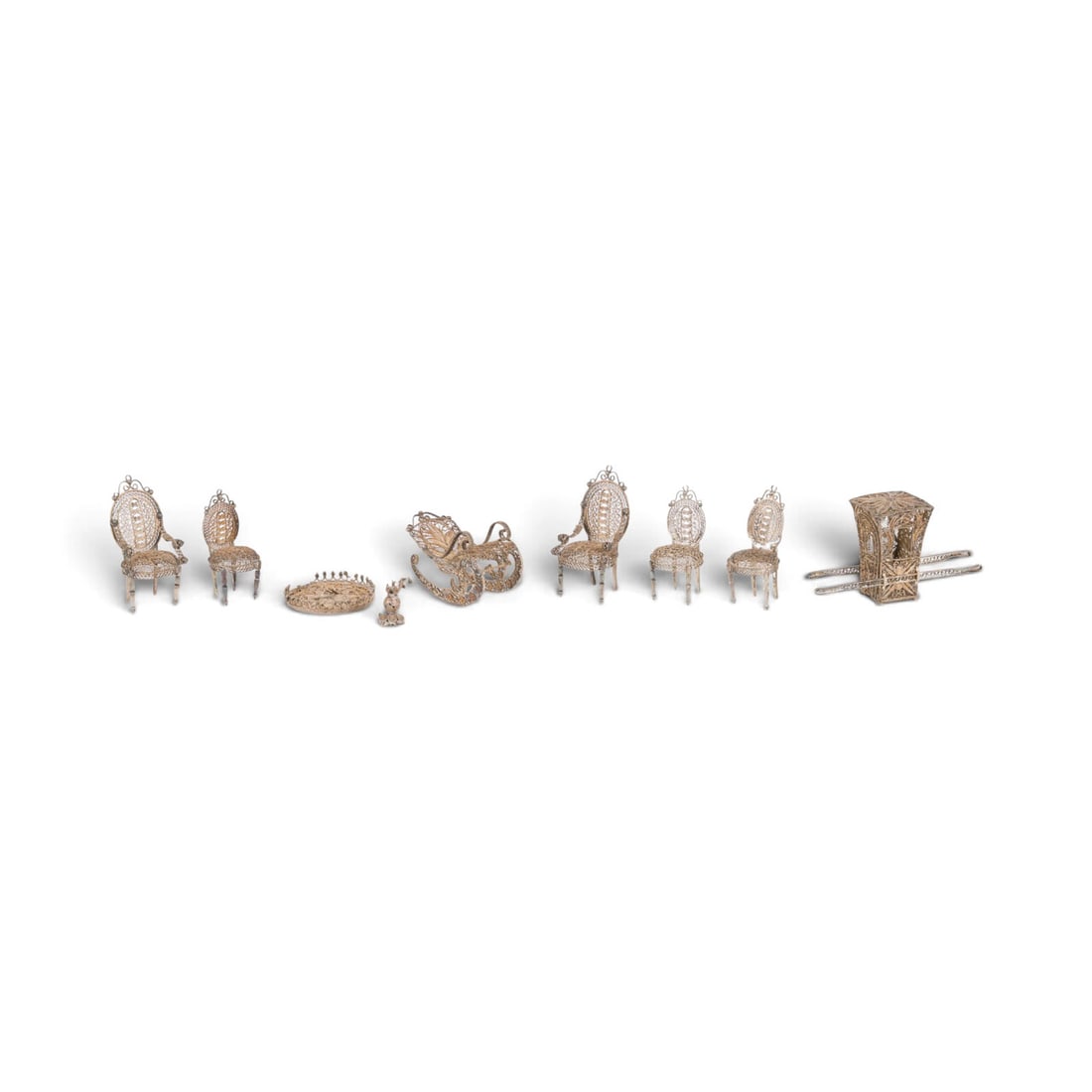 | ACHTTEILIGE SAMMLUNG MINIATUR-MOeBEL: ACHTTEILIGE SAMMLUNG MINIATUR-MOeBEL Niederlande, um 1880 Silber, Filigranarbeit. Ges.-Gew. 54 g, H. 3,5-5 cm. Bestehend aus: 1 runden Tisch, 1 Saenfte, 1 Schaukelstuhl, 6 Stuehlen. Runder Tisch