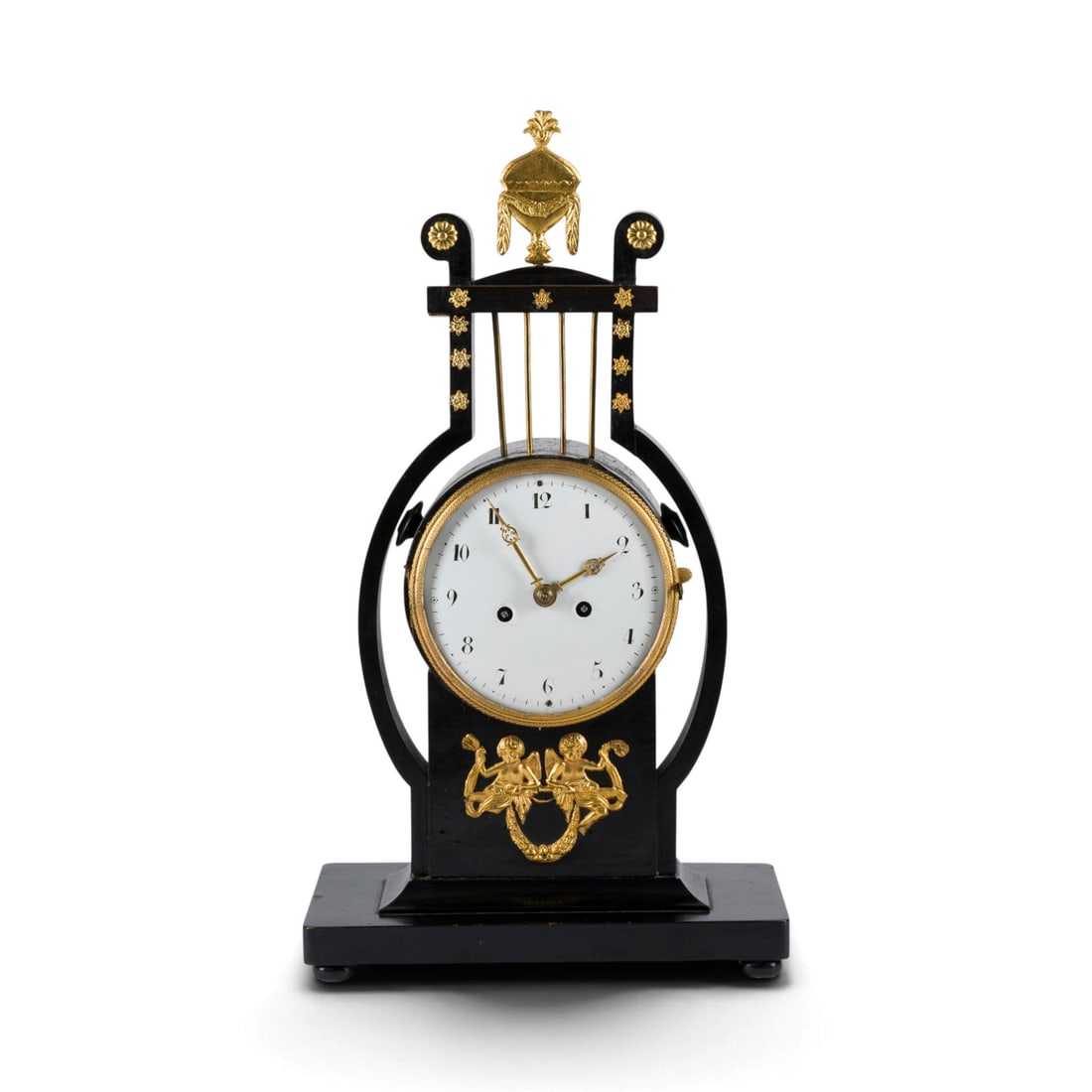 | TISCHUHR IM EMPIRESTIL: TABLE CLOCK IN THE EMPIRE STYLE First half of the 19th century Wood, ebonized, partially gilded, enamel, metal, steel. 40.5 x 22.5 x 12.5 cm. Rectangular base and stylized lyre shape with decorative