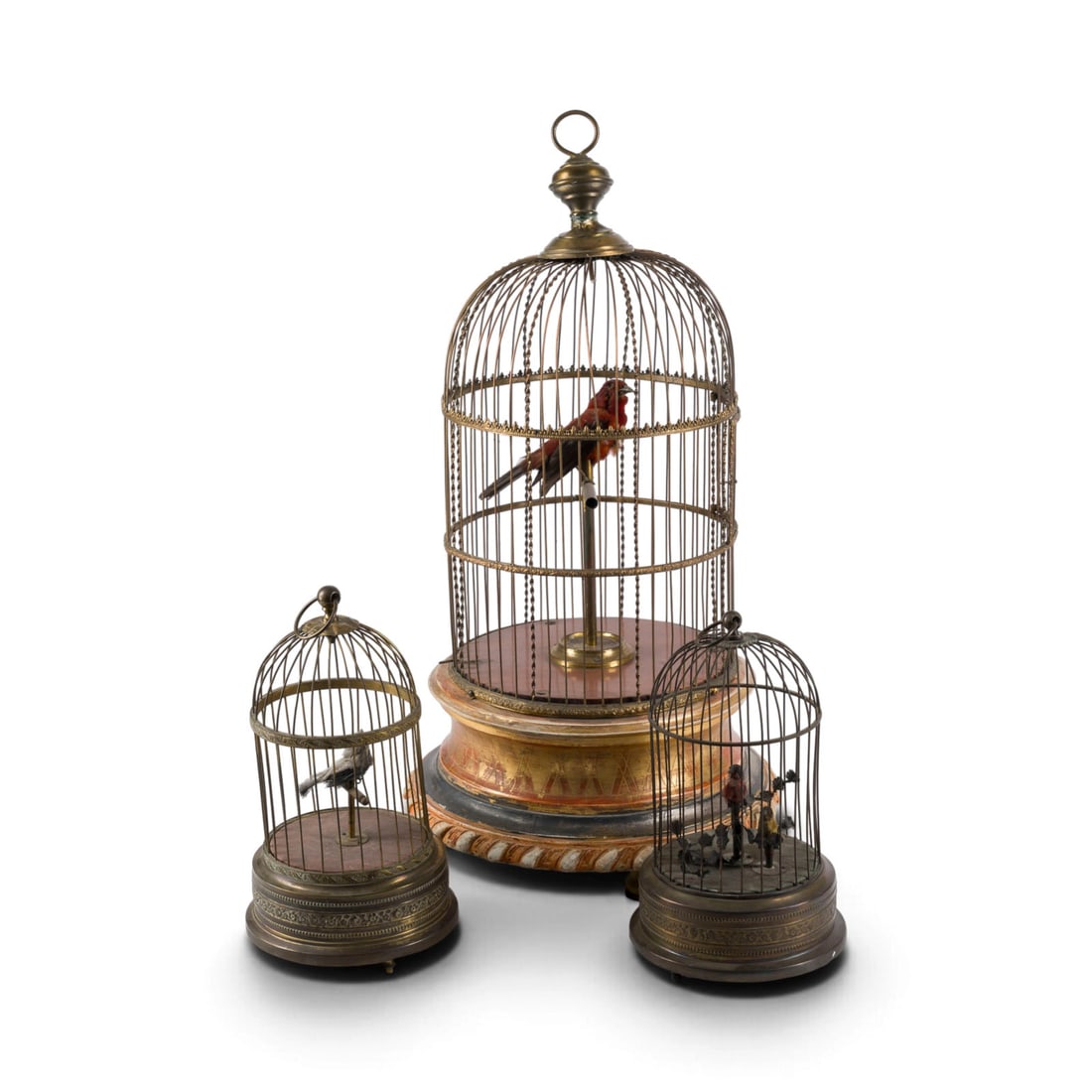 | DREI SINGVOGELAUTOMATEN: THREE SINGING BIRD PLAYERS circa 1900 Wood, polychrome painted, metal, springs. Approx. 28 x 16 x 16 cm / 61 x 32 x 32 cm. Two with spring-driven mechanisms in metal cages with carrying rings, one wit