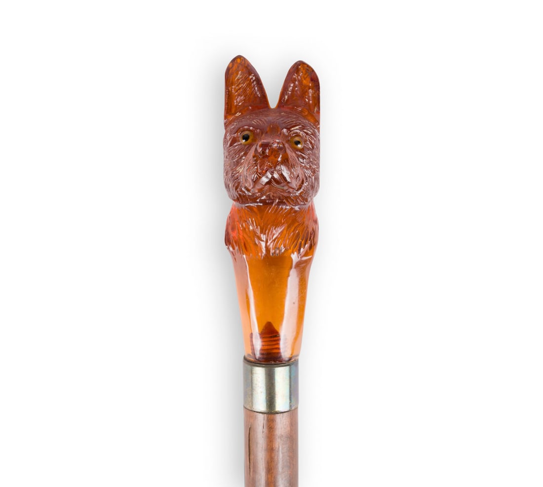 | FIGUeRLICHER SPAZIERSTOCK 'HUNDEKOPF': FIGURAL WALKING STICK 'DOG'S HEAD' Circa 1900 Wood, metal, probably amber. Total length 92.5 cm. Damaged.FIGUeRLICHER SPAZIERSTOCK 'HUNDEKOPF' um 1900 Holz, Metall, wohl Bernstein. Ges.-L. 92,5 cm. Pa