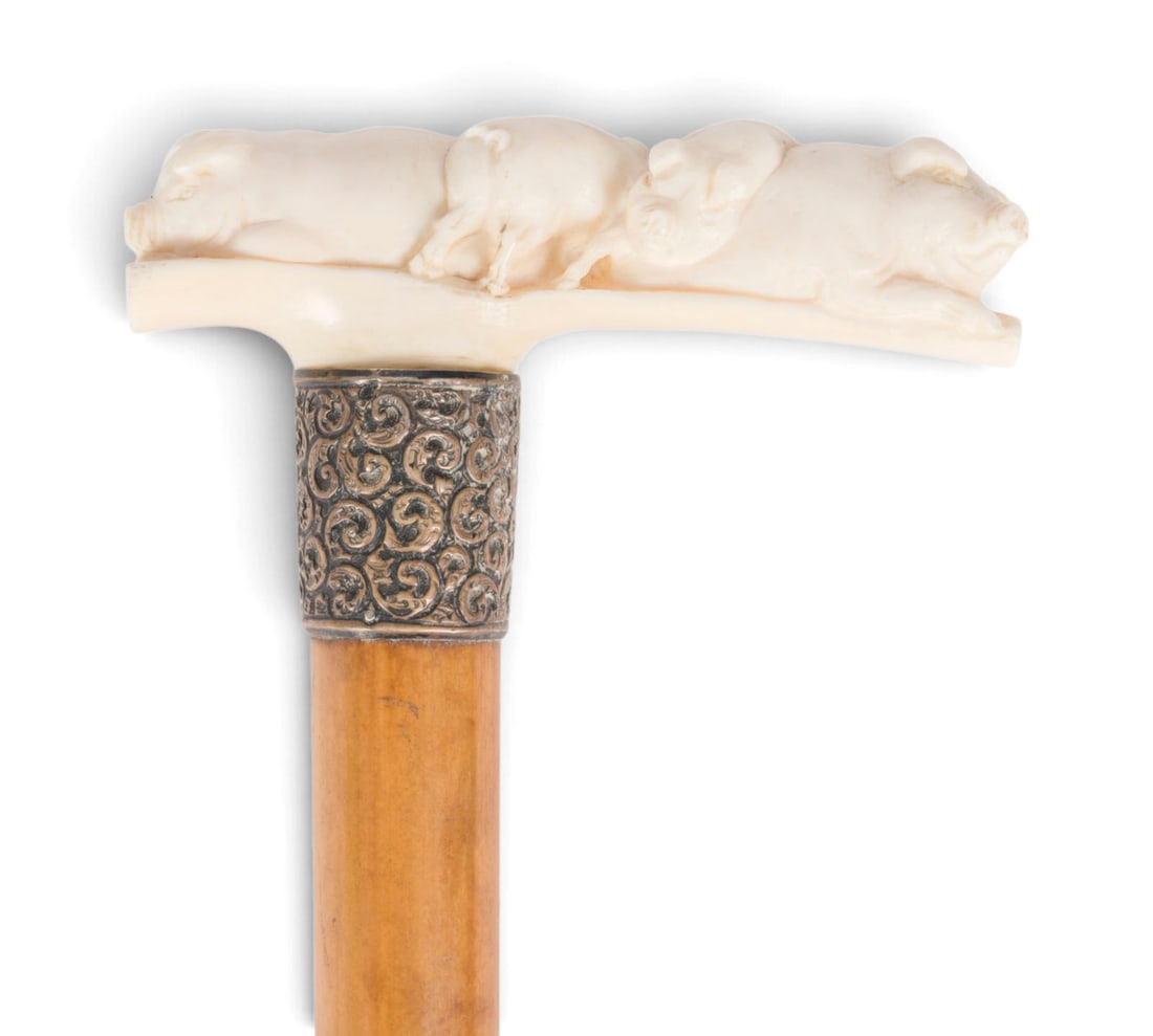 | ZWEI FIGUeRLICHE SPAZIERSTOeCKE: TWO FIGURAL WALKING STICKS Late 19th century Wood, metal (partially silver-plated), ivory, plastic. Total length 90 and 92 cm. Figurally carved handles in the form of a couple and a family of pigs.