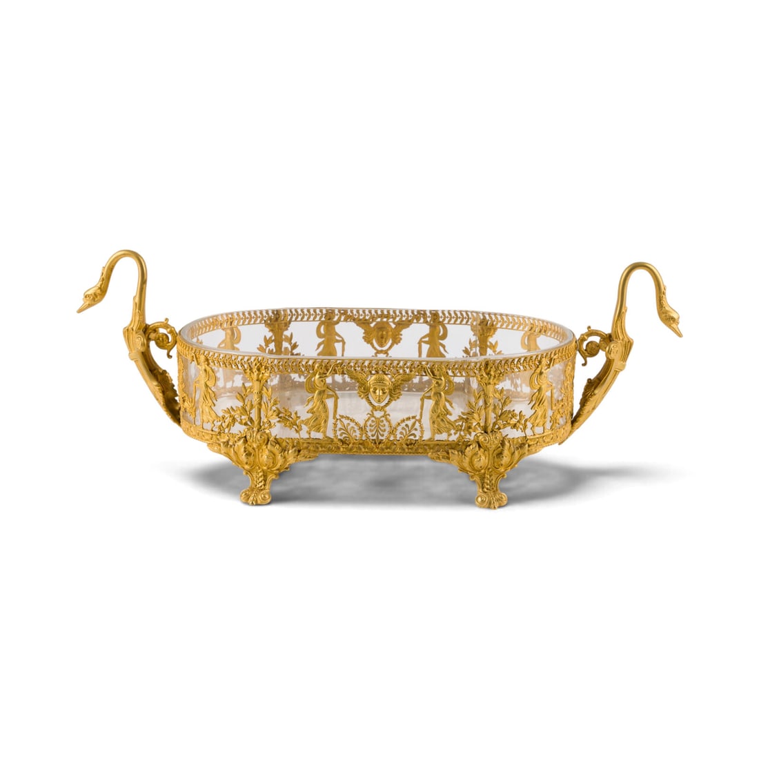 | JARDINIERE IM EMPIRE-STIL: EMPIRE-STYLE JARDINIERE Early 20th century Gilt metal, glass. 17 x 47 x 19 cm. Body featuring intricate figural and floral decoration, raised on four volute feet. Swan-shaped side handles. Clear glass