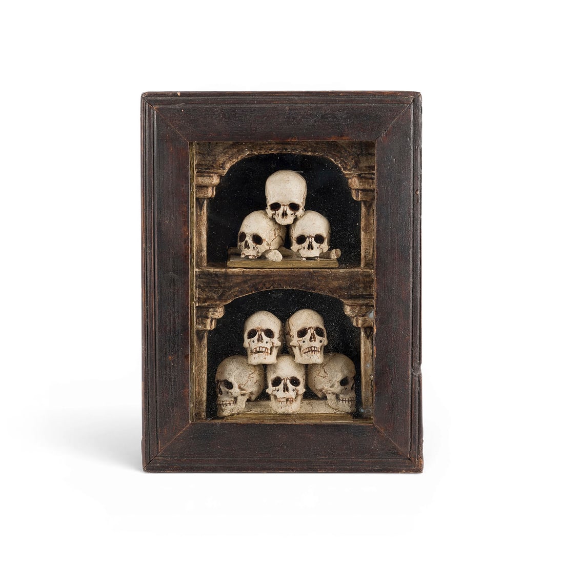 | MEMENTO MORI SCHREIN MIT ACHT TOTENSCHAeDELN: MEMENTO MORI SHRINE WITH EIGHT SKULLS Germany or Austria, 19th century Wood, carved in high relief, polychromed and gilded, framed behind glass. 36.5 x 27 cm. An expressive Memento Mori sculpture feat